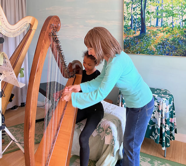 Stephanie Bennett teaches actor Adriana Murigu to play the harp